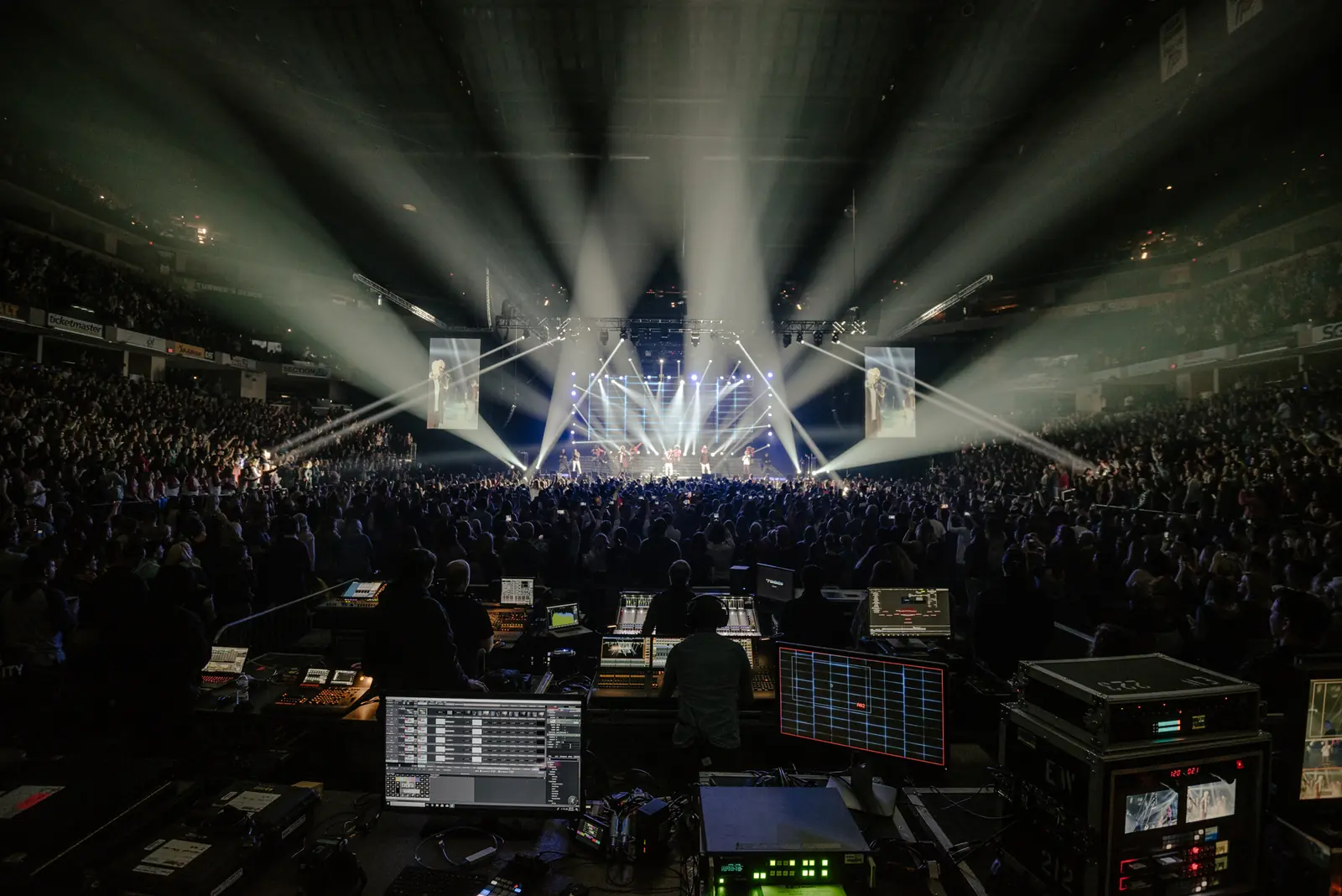 Front-of-house tech position facing a stage full of light beams