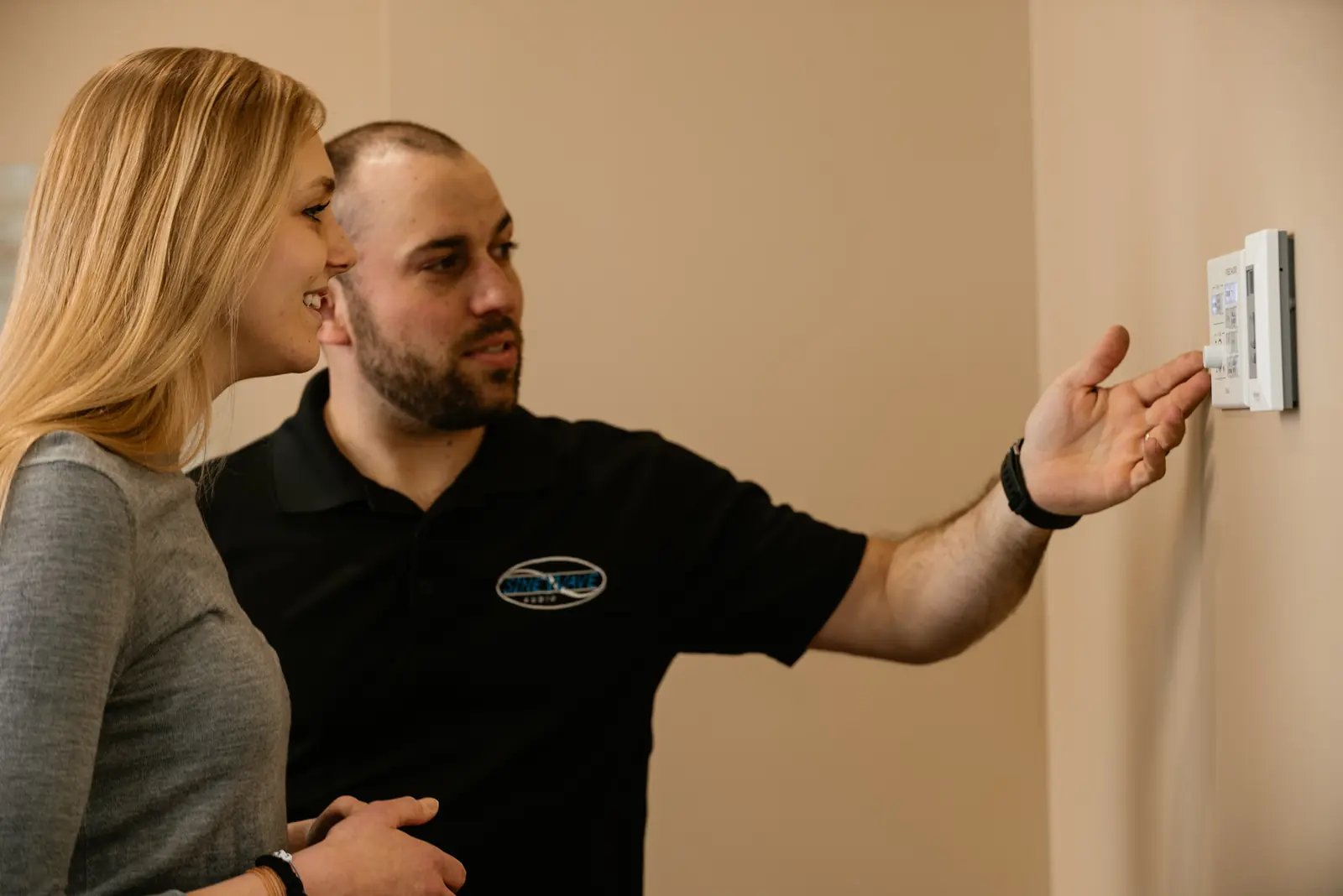 Sinewave technician showing a client a wall-mounted control panel