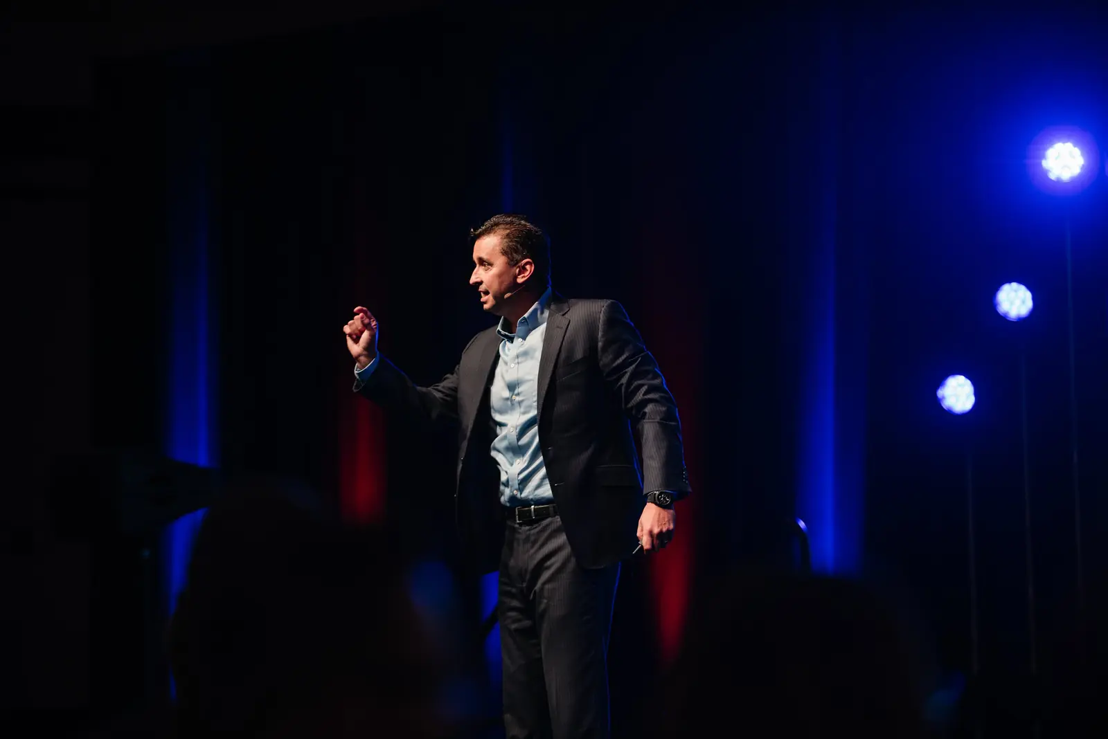 Corporate presenter on a dark stage with accent lighting