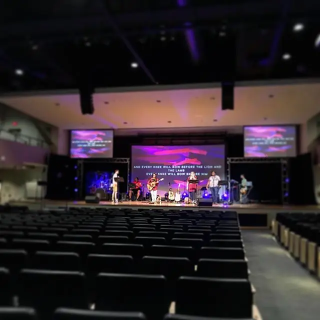 Church worship space with stage lighting and side screens